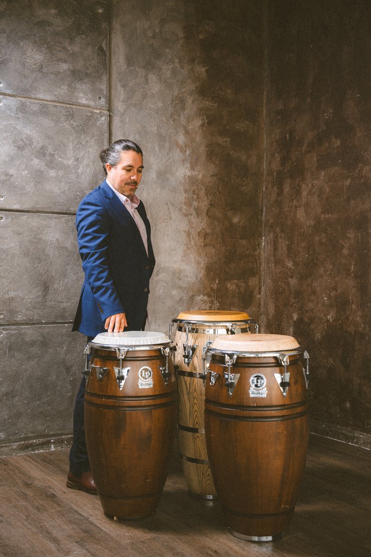 Samuel Torres standing next to congas