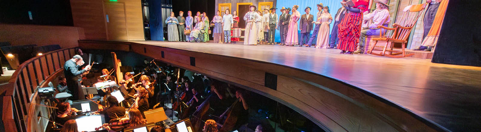 Singers singing on stage and the orchestra playing in the pit for The Elixir of Love opera.