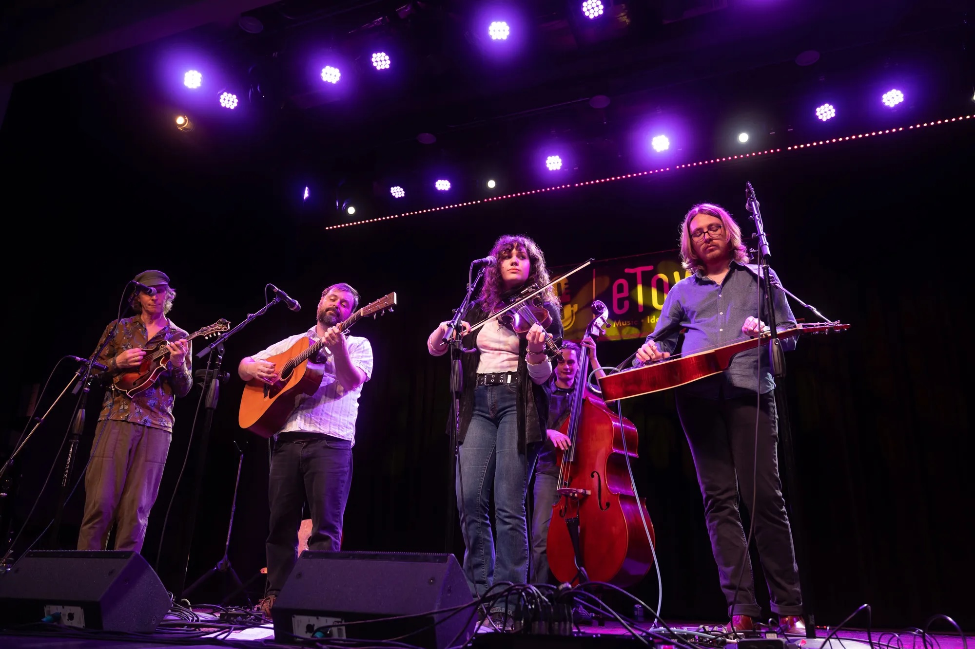 High Lonesome modern bluegrass musical group playing on a stage.